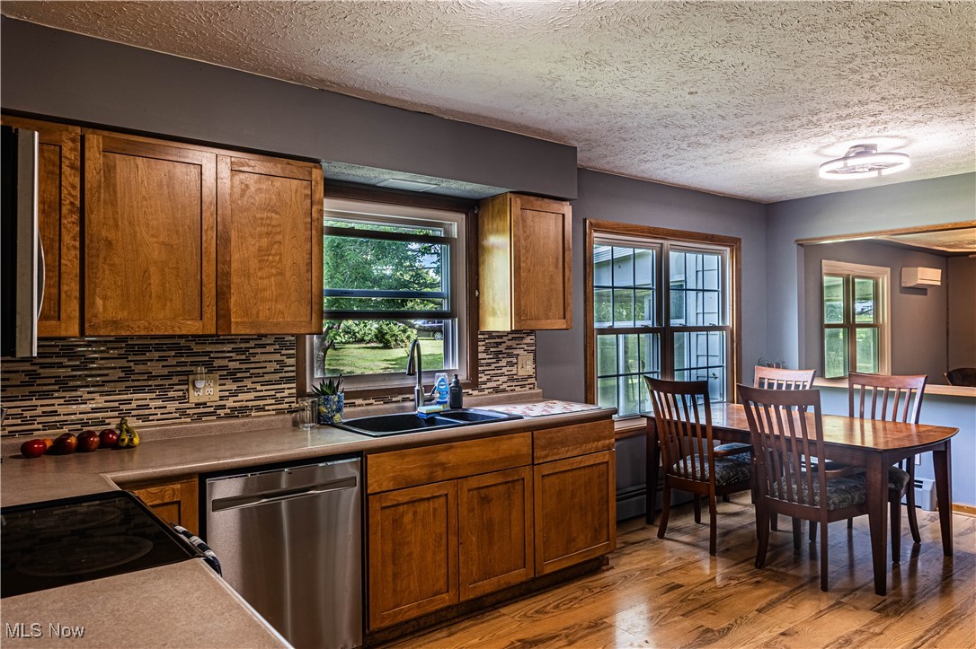 16974 Hawley Road Oberlin, OH 44074 - Photo 7 of 42 Kitchen with stainless steel appliances, light wood-style floors, brown cabinets, tasteful backsplash, and a textured ceiling
