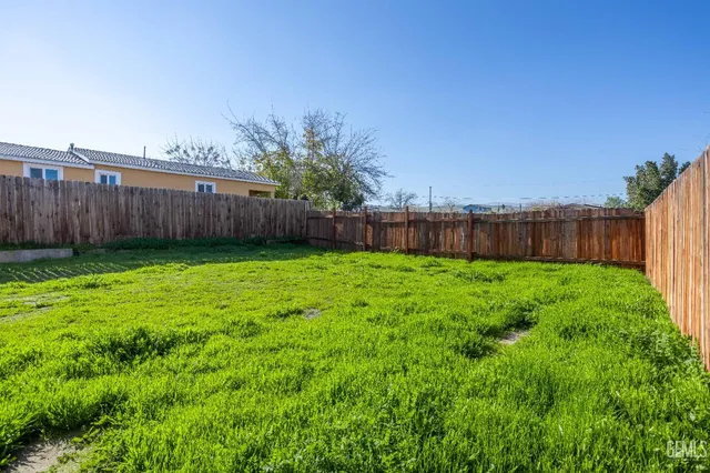 a view of yard with swimming pool and wooden fence