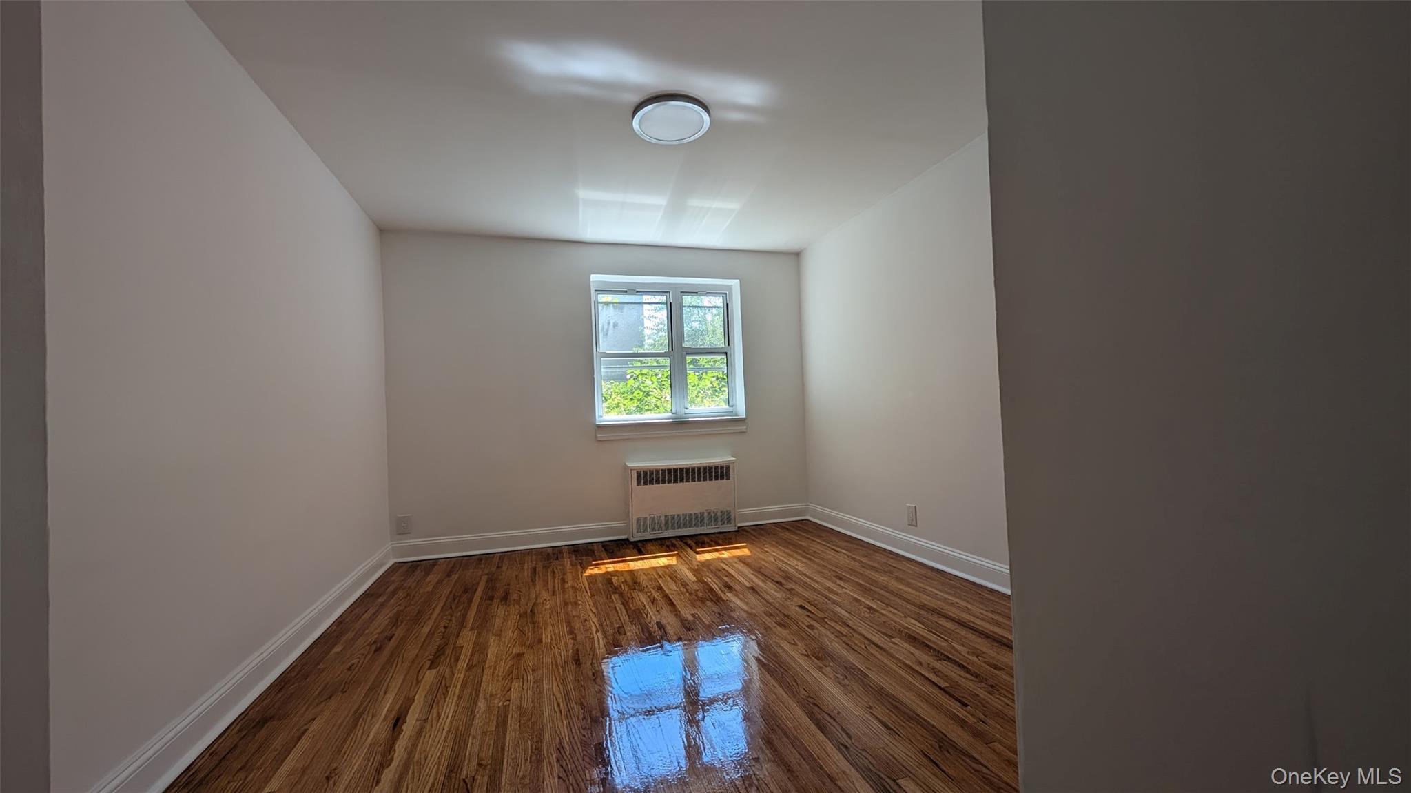 32-06 200th Street, Unit 3F Queens, NY 11361 - Photo 2 of 3 a view of a room with wooden floor and window