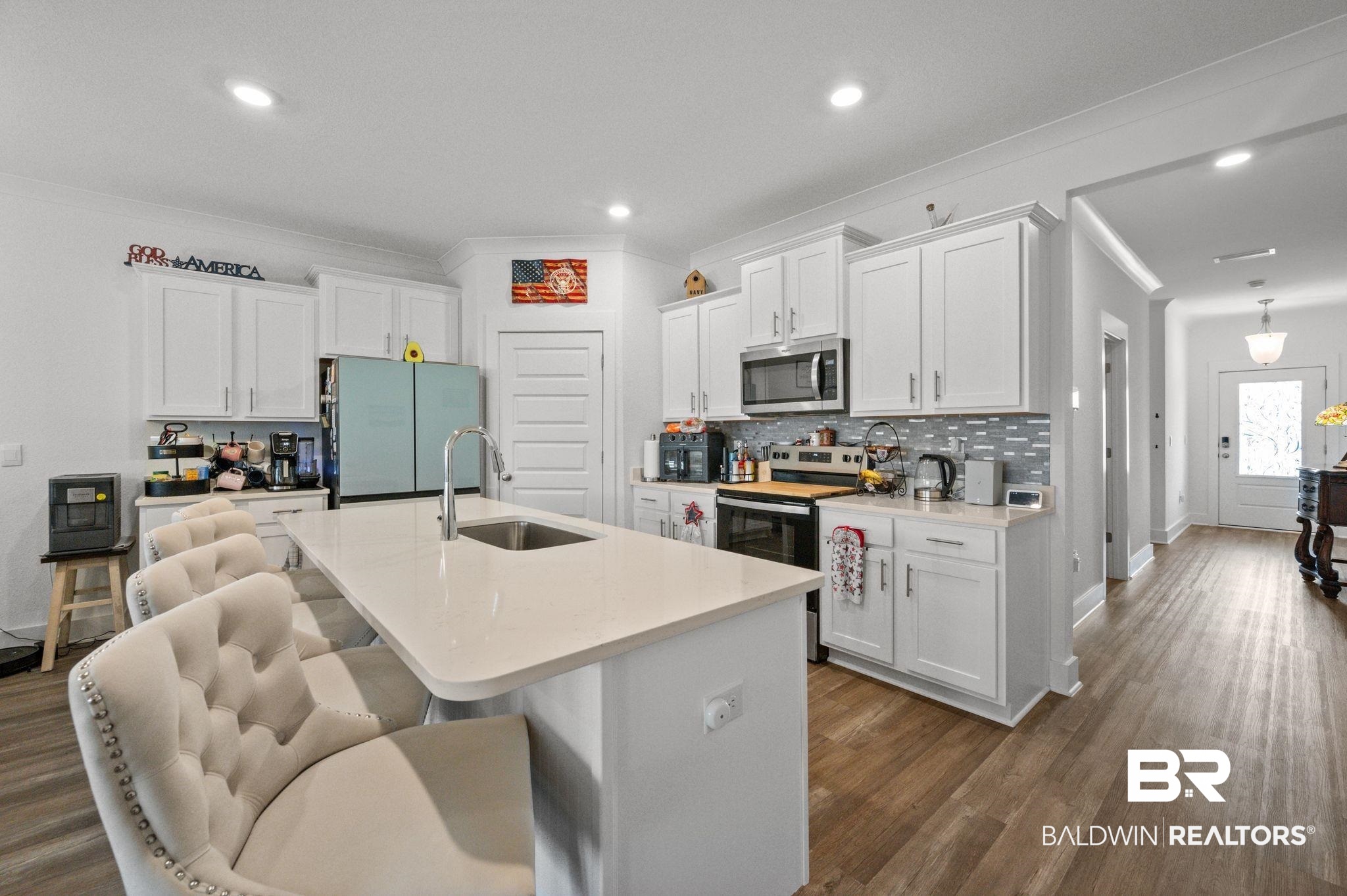 8508 Rosedown Lane Daphne, AL 36526 - Photo 10 of 29 Kitchen with a kitchen breakfast bar, ornamental molding, stainless steel appliances, white cabinetry, and a kitchen island with sink