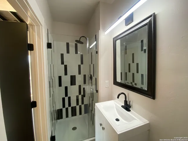 a bathroom with a sink mirror and shower