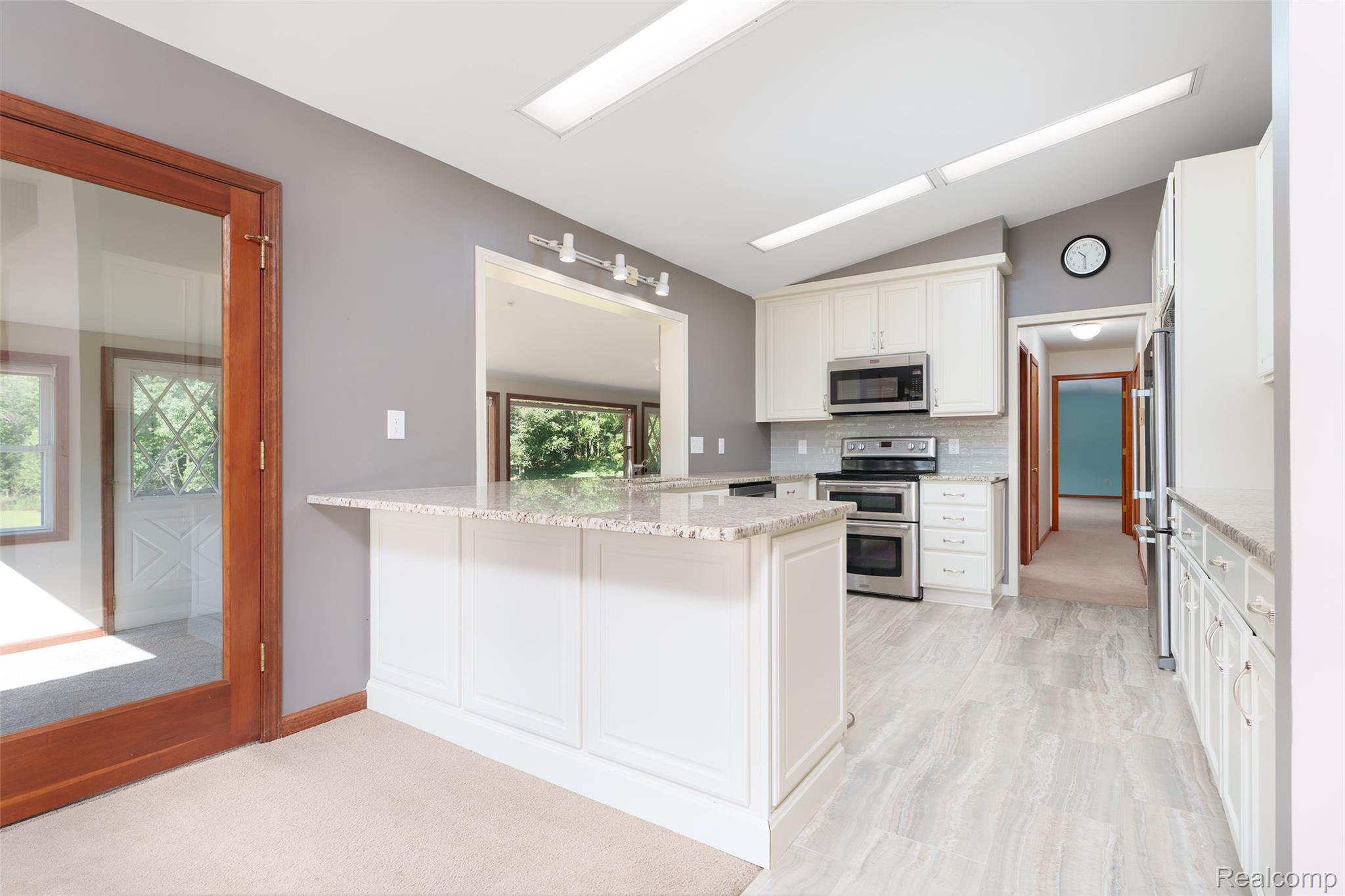 3166 Bigelow Road Howell, MI 48855 - Photo 11 of 50 Kitchen featuring white cabinetry, light-toned stone countertops, stainless steel appliances, and wood-finish flooring