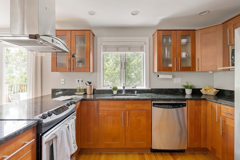 41 Wilson Avenue, Unit 41 Watertown, MA 02472 - Photo 6 of 22 a kitchen with granite countertop wooden cabinets a stove a sink and a window