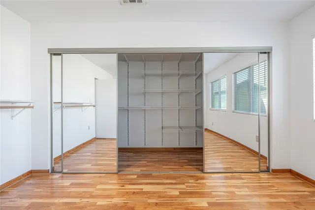 a view of an empty room with wooden floor and closet