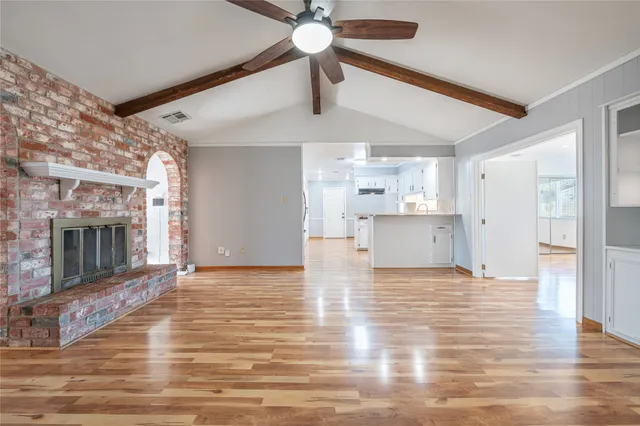 a view of empty room with wooden floor fan and window