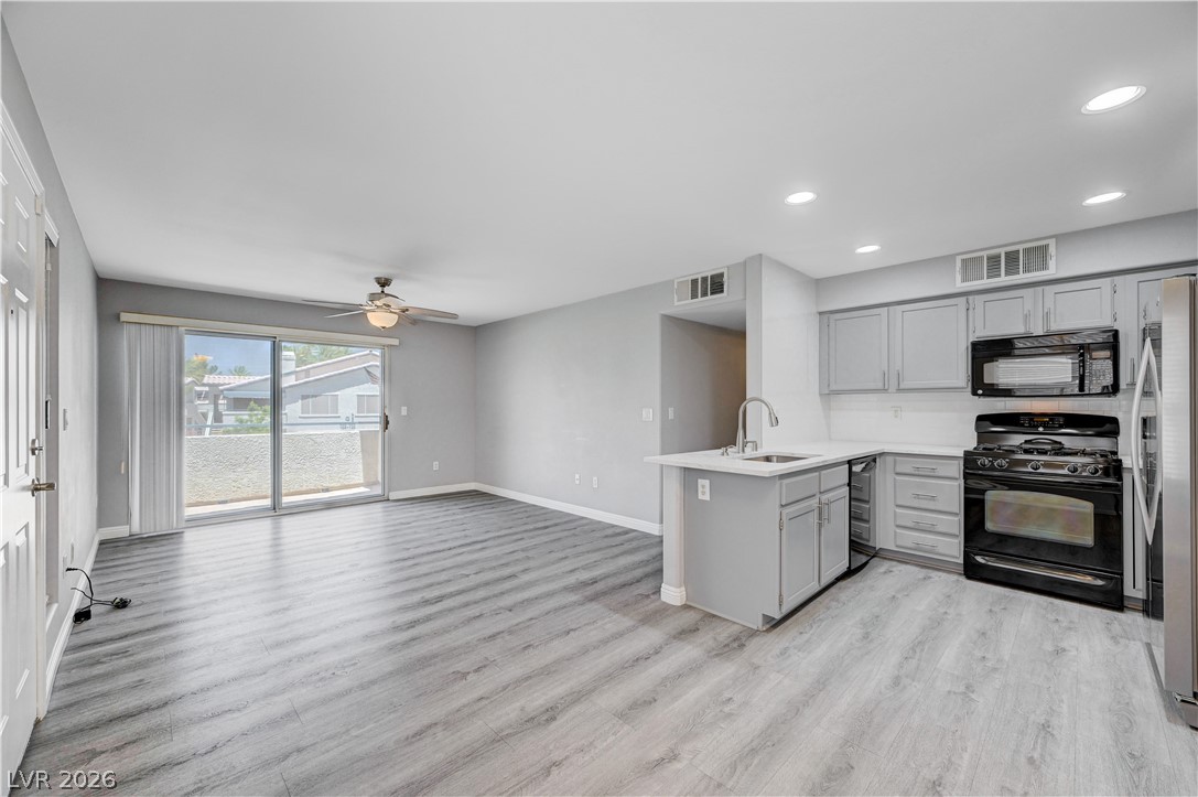 3425 East Russell Road, Unit 223 Las Vegas, NV 89120 - Photo 7 of 47 A combined living and kitchen area features modern cabinetry, a kitchen island, and direct outdoor access through sliding glass doors.