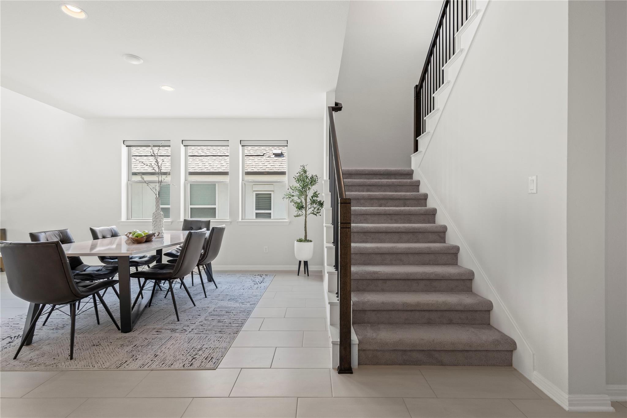 1128 Villa Rialto View Leander, TX 78641 - Photo 13 of 40 Clean lines and neutral tones define this bright dining area, seamlessly flowing into a carpeted staircase.