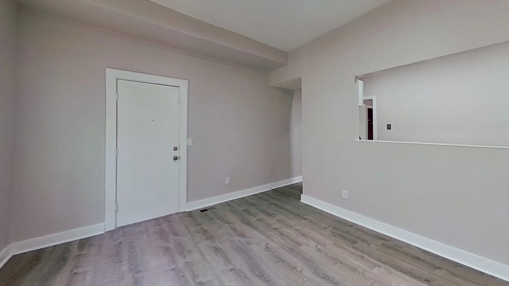 94 Walnut Avenue Boston, MA 02119 - Photo 7 of 9 an empty room with wooden floor and windows
