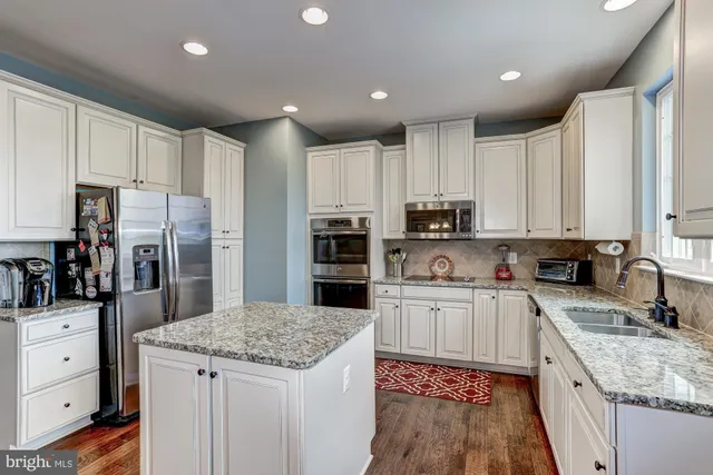 a kitchen with kitchen island granite countertop a sink stove and refrigerator