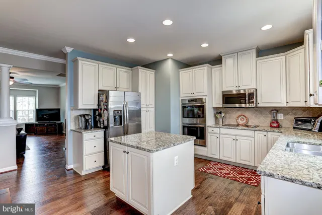 a kitchen with kitchen island granite countertop stainless steel appliances refrigerator oven stove microwave and cabinets