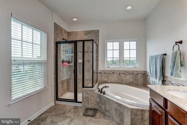 a bathroom with a tub a sink and a large mirror