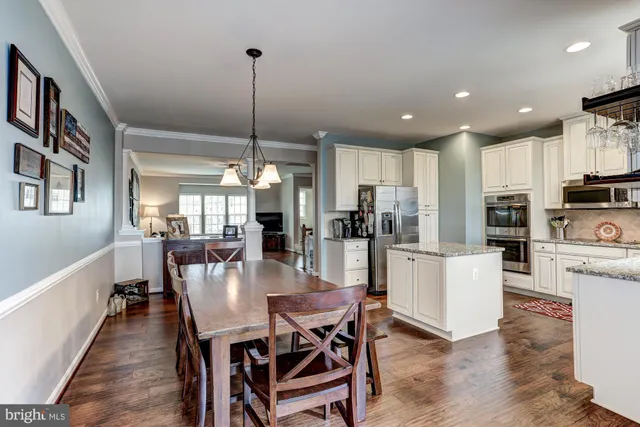 a dining room with kitchen island stainless steel appliances furniture a dining table and chairs