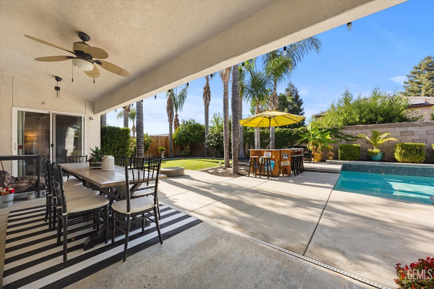 Undisclosed Address Bakersfield, CA 93312 - Photo 49 of 61 a view of a swimming pool with a table and chairs under an umbrella