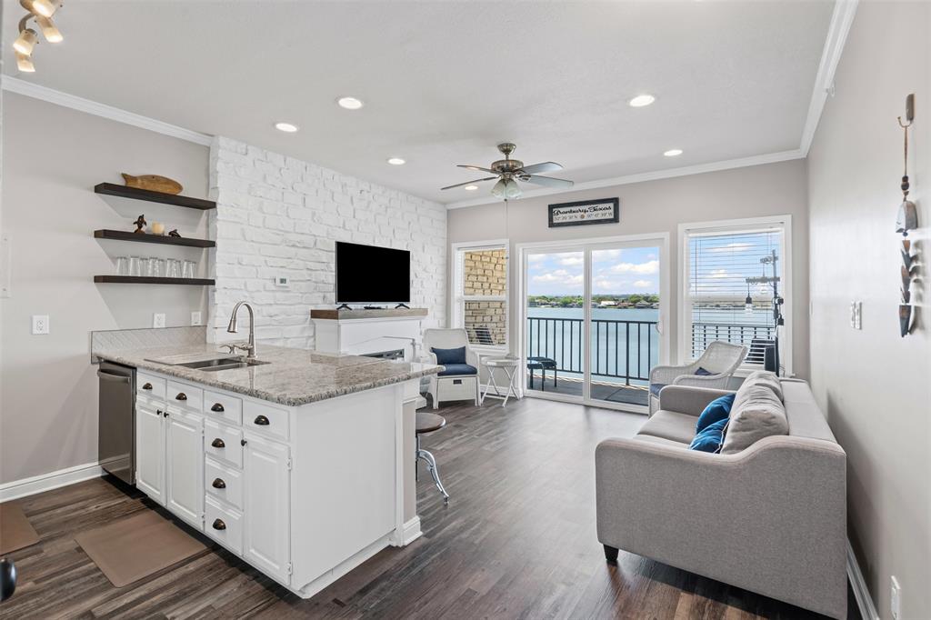 401 East Pearl Street, Unit 2306 Granbury, TX 76048 - Photo 16 of 17 Great room featuring open floor plan, a granite peninsula, crown molding, and feature wall of white stone.