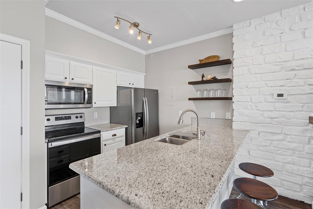 401 East Pearl Street, Unit 2306 Granbury, TX 76048 - Photo 13 of 17 Efficient galley style kitchen with large prep areas, undermounted sink, and full size refrigerator.