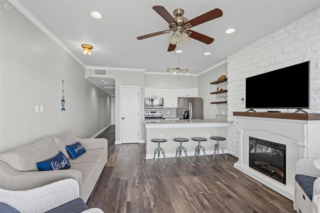 401 East Pearl Street, Unit 2306 Granbury, TX 76048 - Photo 14 of 17 Living room with electric fireplace, ornamental molding, vinyl floors, and ceiling fan
