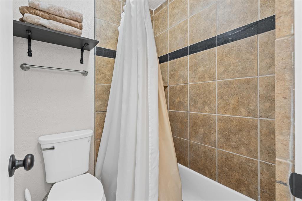 401 East Pearl Street, Unit 2306 Granbury, TX 76048 - Photo 10 of 17 Full bath with toilet and tiled shower / bath combo with shower curtain