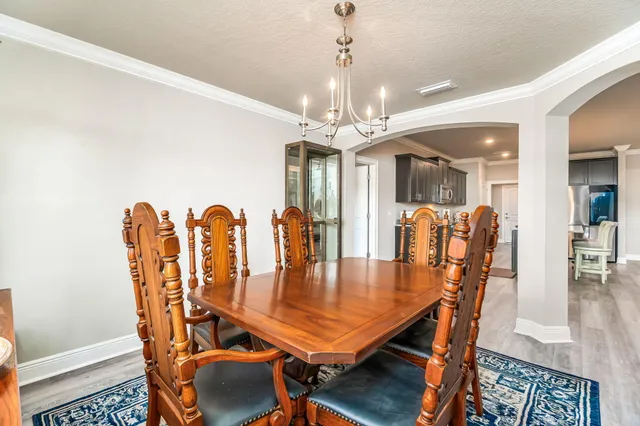 a dining room with furniture a chandelier and wooden floor
