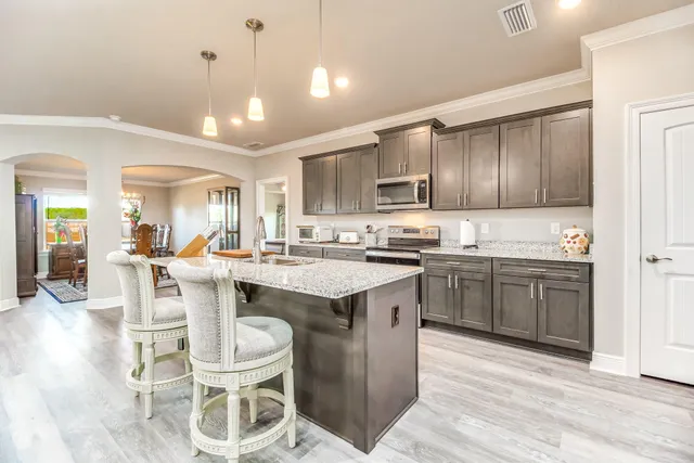 a kitchen with a sink stove cabinets and wooden floor