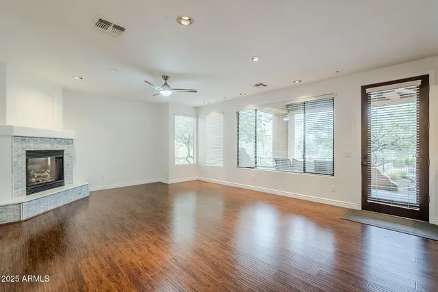 a view of an empty room with a window and wooden floor