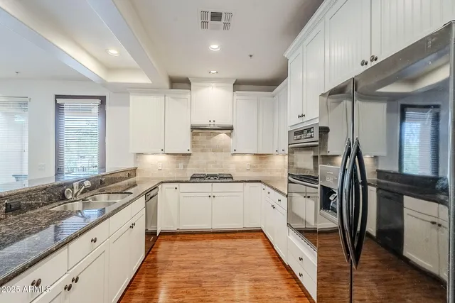 a large kitchen with stainless steel appliances granite countertop a stove top oven a sink a dining table and chairs