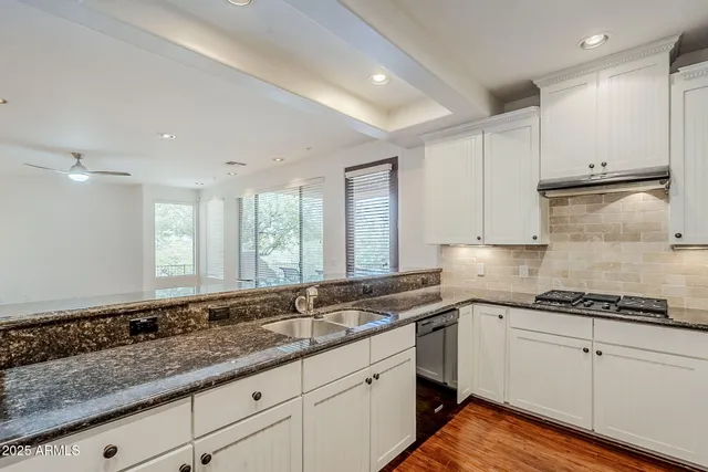 a kitchen with granite countertop white cabinets white appliances and a sink
