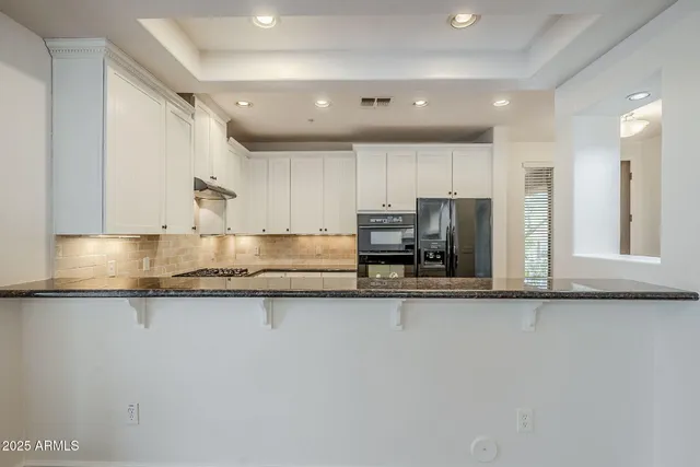 a kitchen with stainless steel appliances granite countertop a sink refrigerator and cabinets
