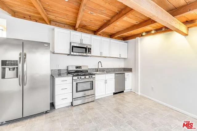 a kitchen with stainless steel appliances granite countertop a refrigerator and white cabinets