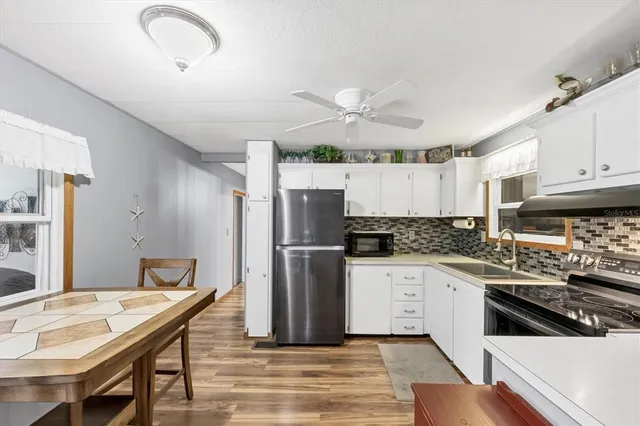 a kitchen with granite countertop a stove a sink dishwasher a refrigerator with white cabinets and wooden floor