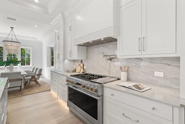 a kitchen with stainless steel appliances a stove a sink dishwasher and white cabinets with wooden floor