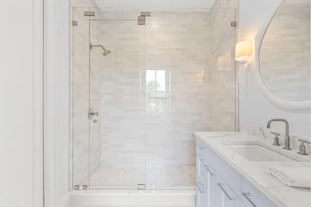 a bathroom with a granite countertop sink a mirror and shower