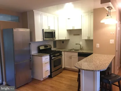 a kitchen with granite countertop a sink appliances and cabinets