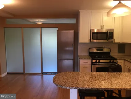 a kitchen with granite countertop a refrigerator and a stove top oven