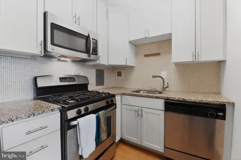 a kitchen with stainless steel appliances granite countertop a stove a microwave and a white cabinets