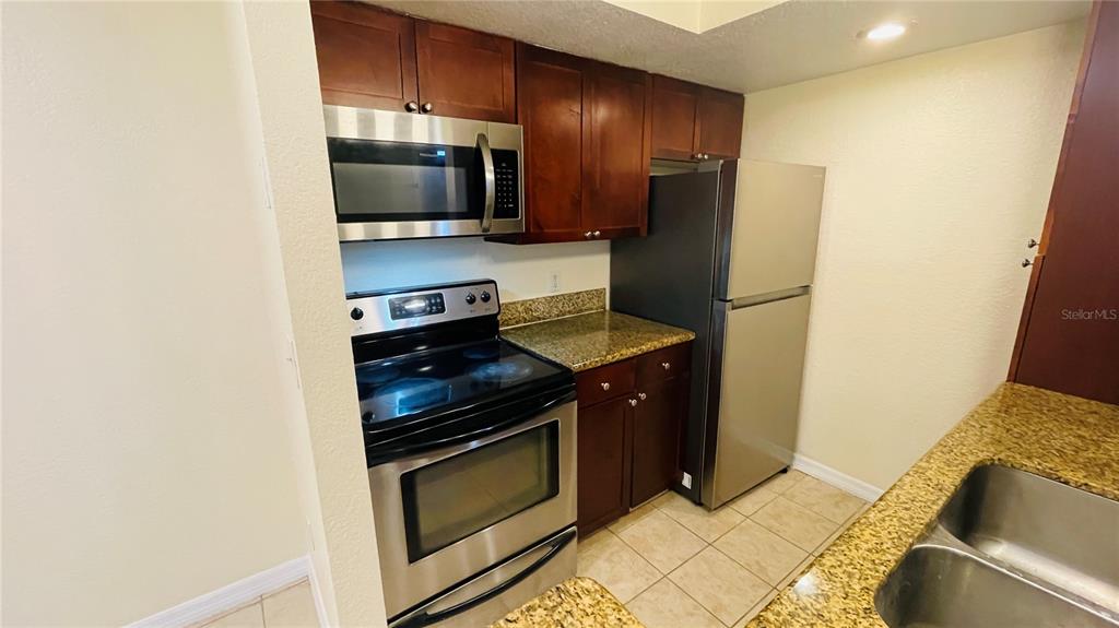 5120 Conroy Road, Unit 13 Orlando, FL 32811 - Photo 5 of 25 a kitchen with a refrigerator stove and microwave