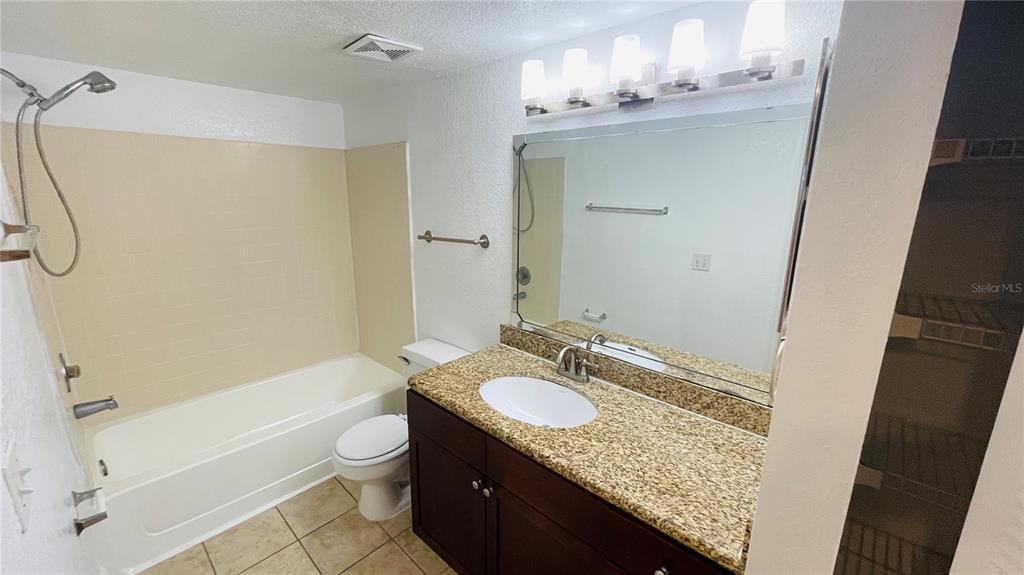 5120 Conroy Road, Unit 13 Orlando, FL 32811 - Photo 9 of 25 a bathroom with a granite countertop sink a toilet and shower
