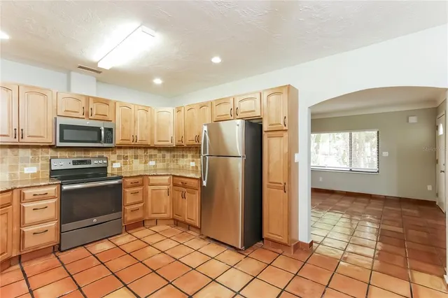 a kitchen with stainless steel appliances granite countertop a refrigerator and a stove top oven