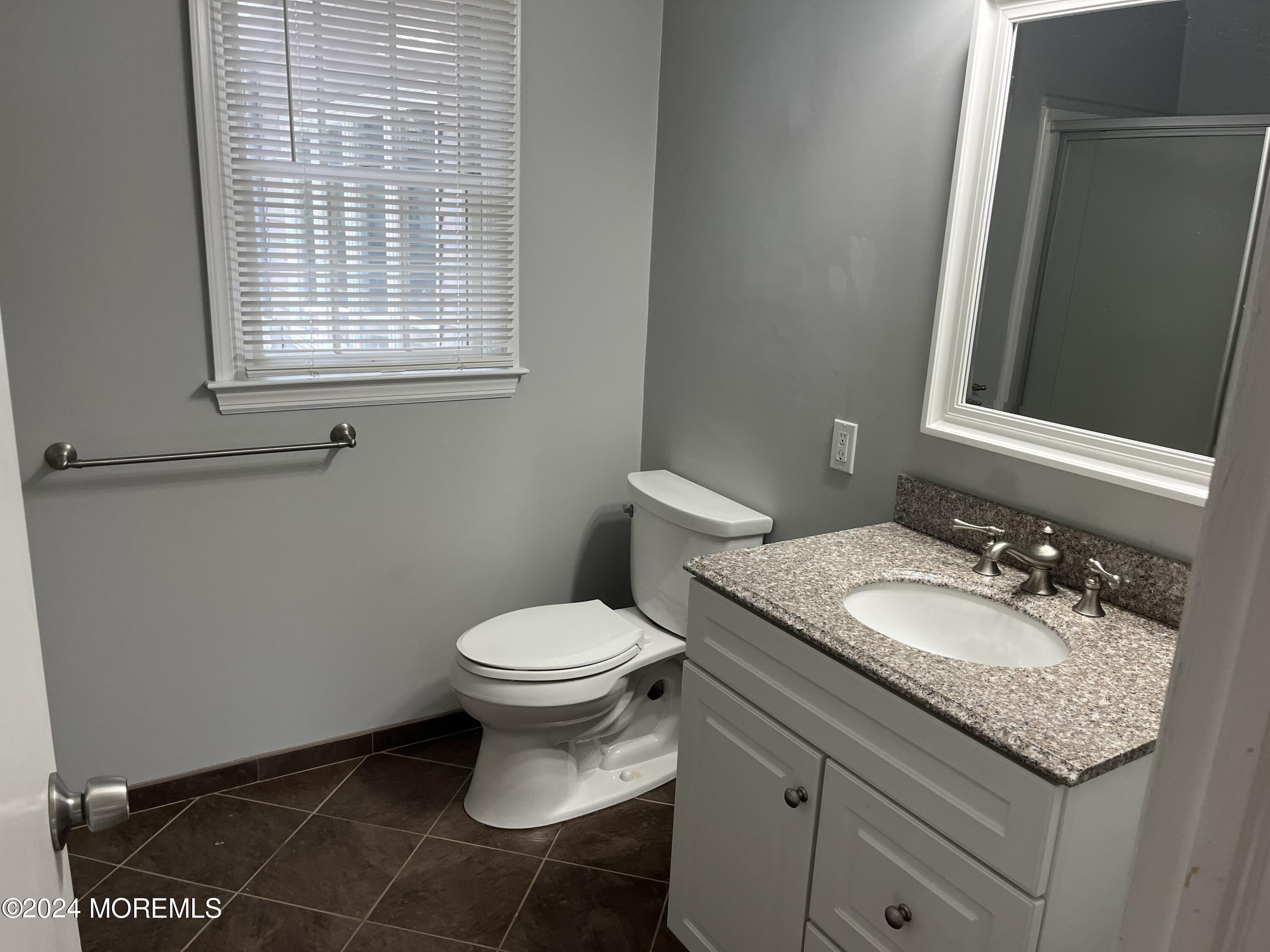 22 Robin Road Rumson, NJ 07760 - Photo 20 of 24 a bathroom with a granite countertop toilet a sink a mirror and a window