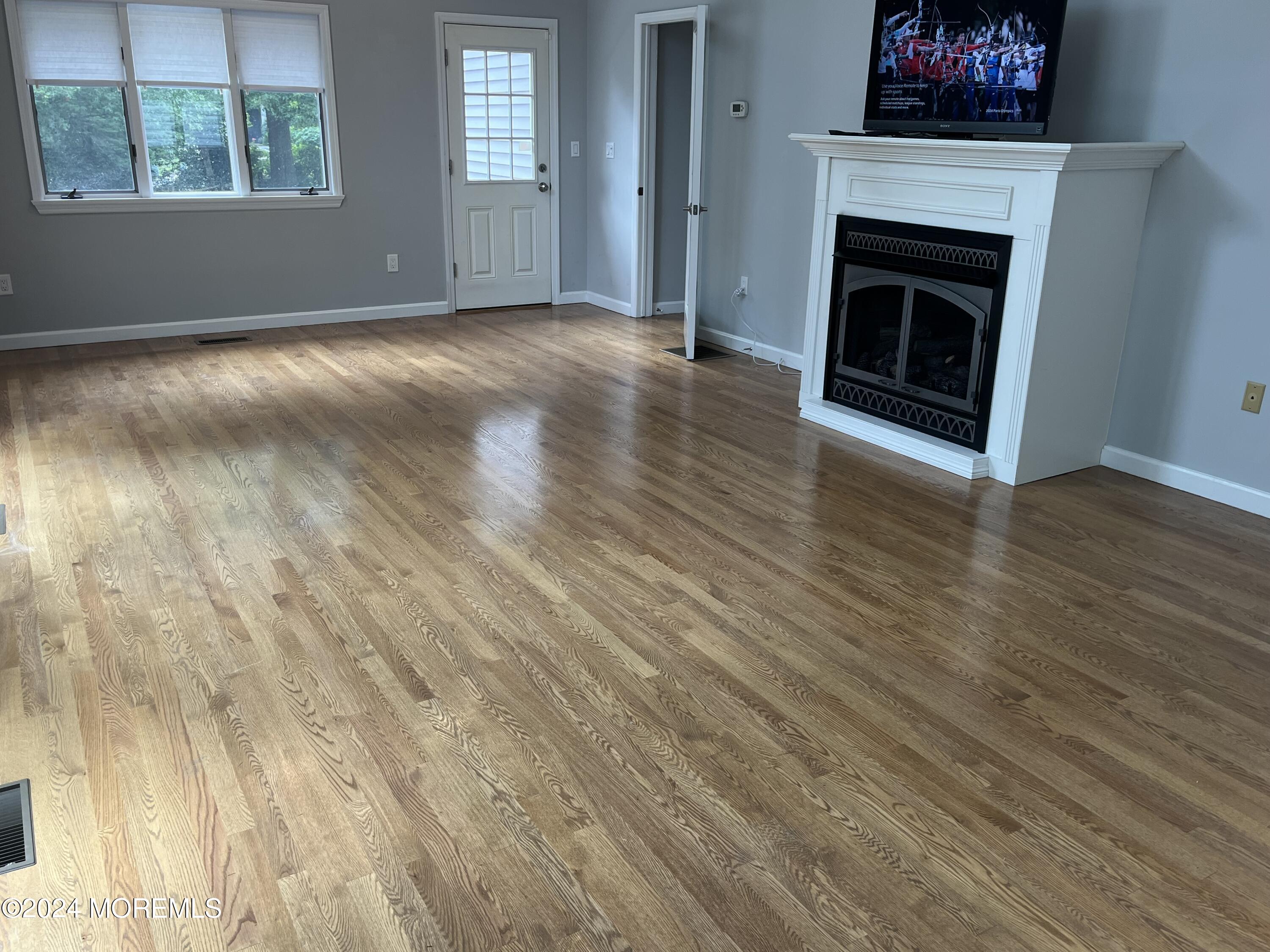 22 Robin Road Rumson, NJ 07760 - Photo 10 of 24 an empty room with wooden floor a fireplace and windows