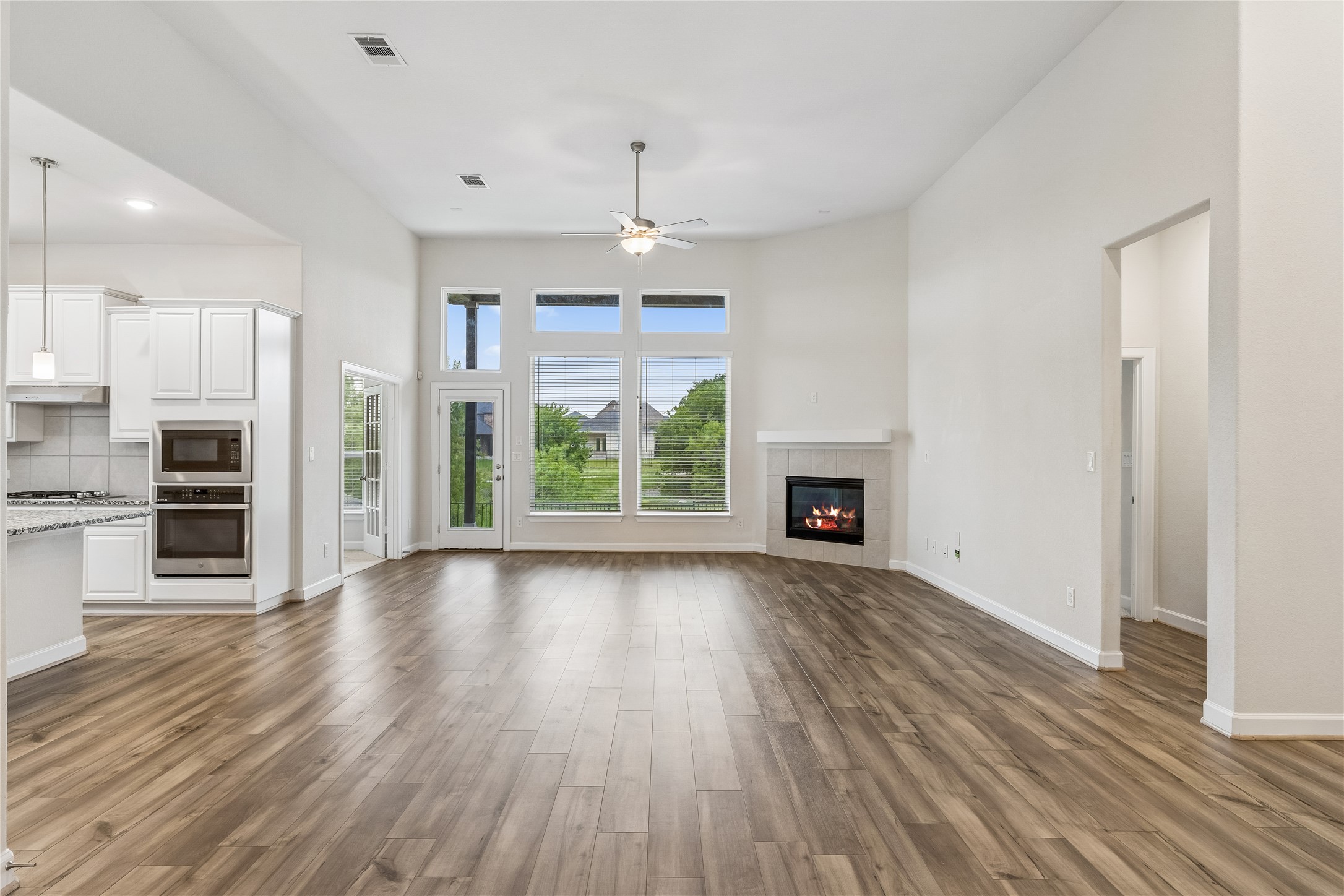 298 Wild Pecan Loop Buda, TX 78610 - Photo 3 of 40 an empty room with wooden floor a ceiling fan and windows