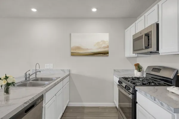 a kitchen with stainless steel appliances granite countertop a sink stove and microwave