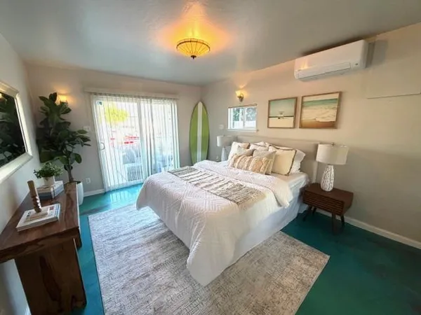 a bedroom with a bed table flowerpot and window