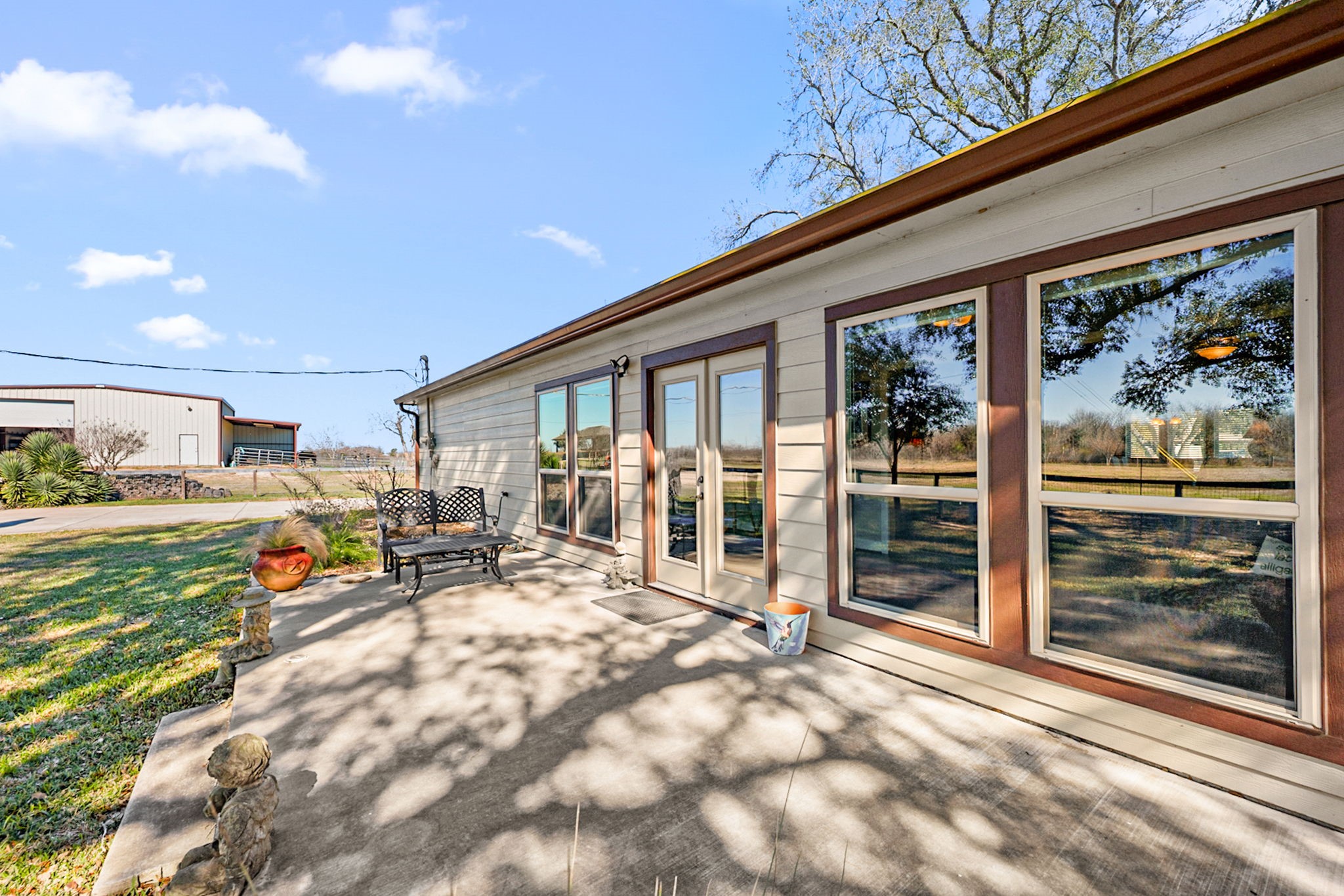26253 Sharp Road Katy, TX 77493 - Photo 16 of 25 Enjoy relaxed country living with this paved back patio—perfect for morning coffee or evening gatherings—overlooking the property’s impressive 40x40 barn featuring a pool and outdoor kitchen, ideal for entertaining, hobbies, or hosting unforgettable weekends at 26253 Sharp Road.