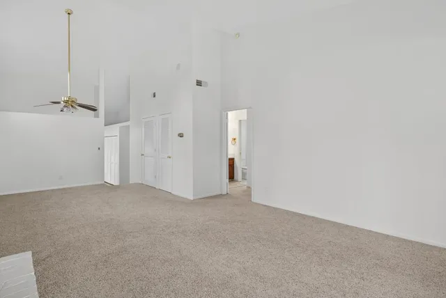 a view of a big room with windows and chandelier fan