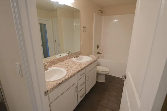 a bathroom with a granite countertop sink a toilet and a shower