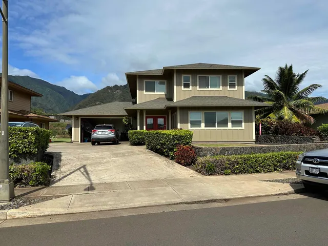 a front view of a house with yard and parking