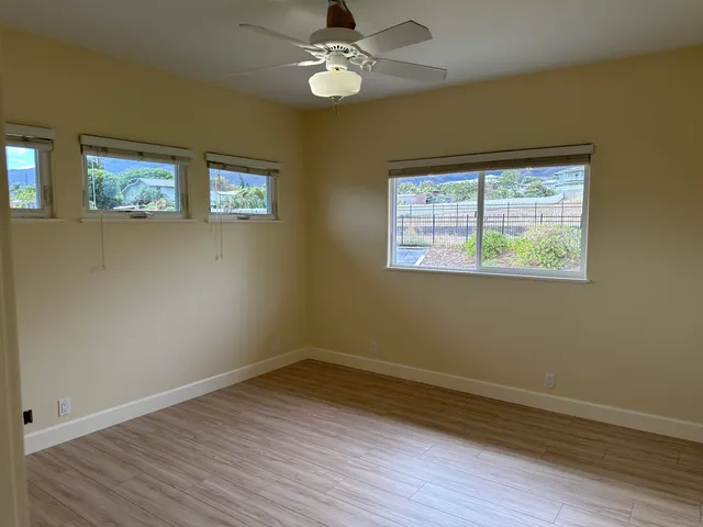 a view of empty room with wooden floor and fan