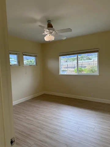 a view of empty room with wooden floor and fan