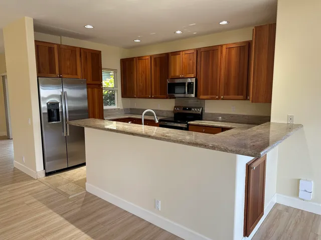 a kitchen with stainless steel appliances granite countertop a refrigerator a sink a stove a microwave and wooden cabinets