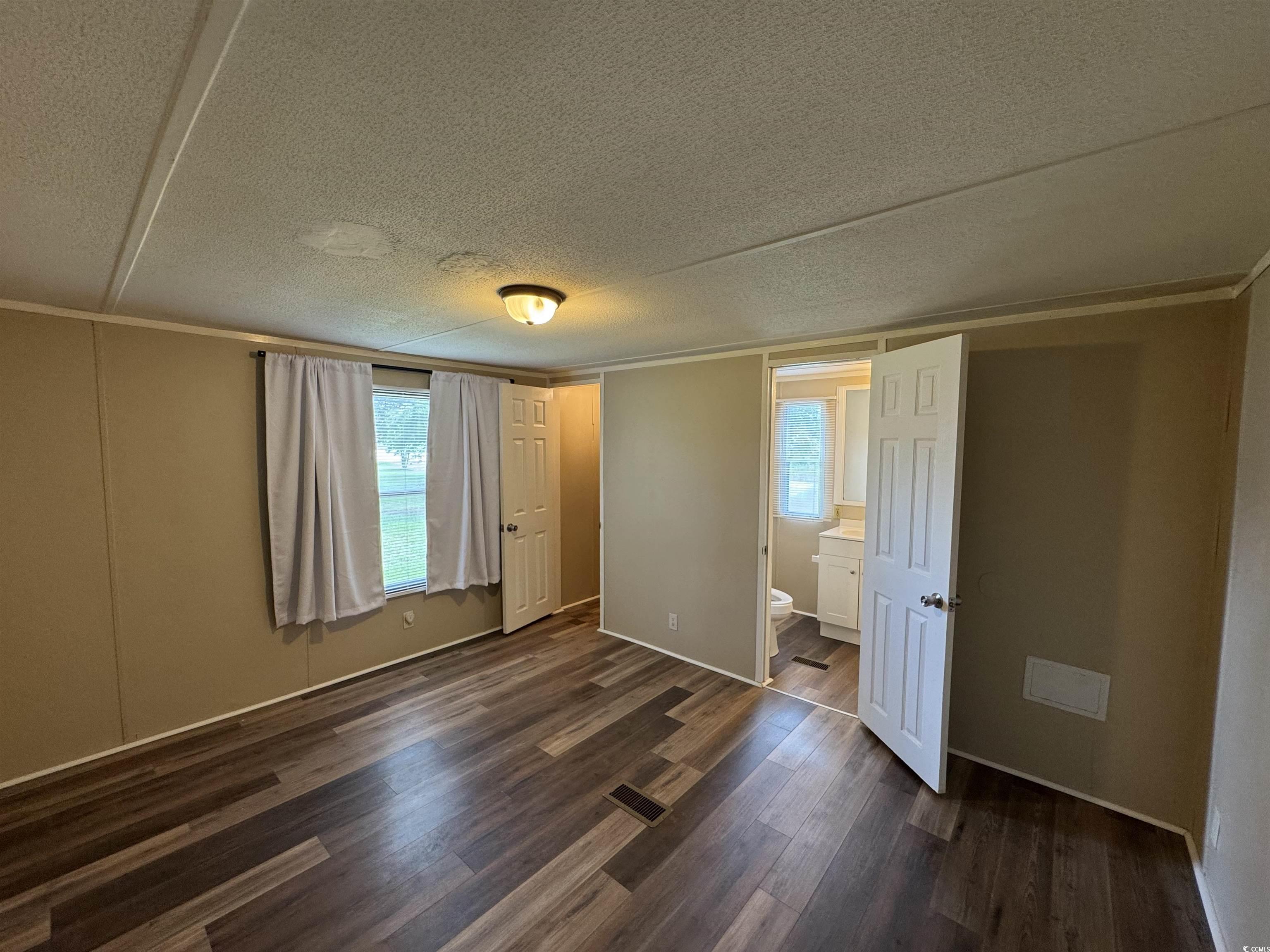Tbd Still Pond Road Conway, SC 29526 - Photo 9 of 18 Unfurnished bedroom featuring dark wood-style floors, a textured ceiling, crown molding, and ensuite bath